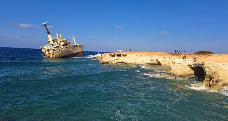 Famous rusted EDRO III shipwreck leaning off a rocky Cypriot coast with tourists nearby