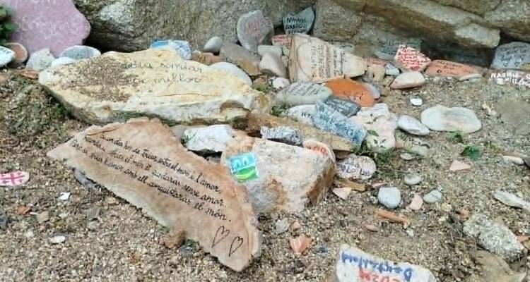 Collection de pierres décorées et de messages manuscrits sur une petite étendue de galets de plage.