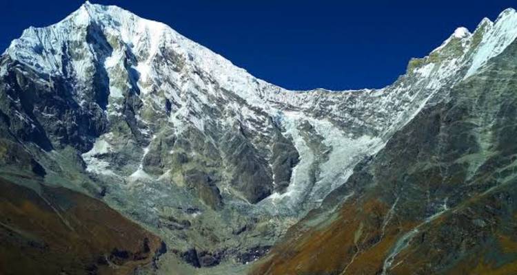 Dramatic Himalayan peak with a sheer glacier-scarred face rising against a cobalt sky.