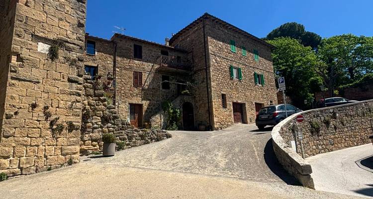 Rue tranquille d'un petit hameau en pierre avec voiture garée et maisons rustiques sous un ciel bleu