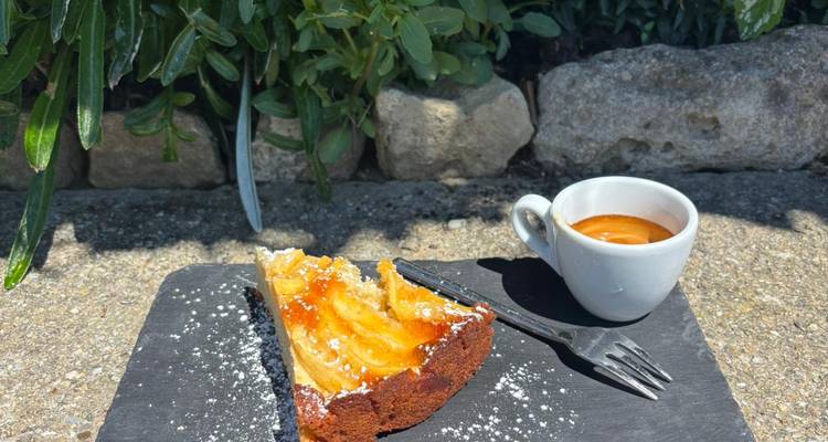 Tranche de gâteau aux pommes saupoudrée de sucre et tasse d'espresso sur une assiette en ardoise en plein air