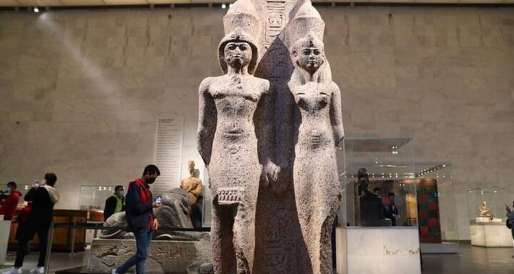 Grupo de estatuas de granito exhibido en una amplia sala de museo con visitantes cerca