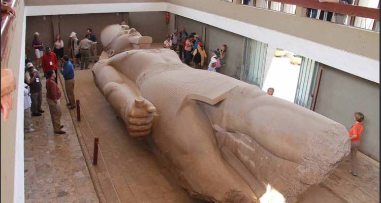 Colosal estatua reclinada de Ramsés II exhibida dentro del museo con visitantes alrededor