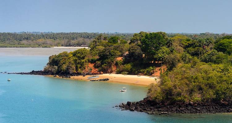 Duplicate coastal cove image with red cliffs, sandy beach and small boat on blue water.