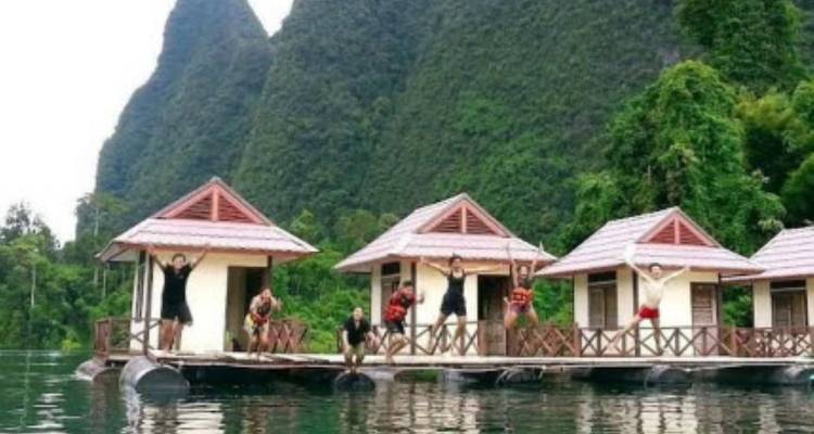 Les voyageurs se déplacent entre des bungalows flottants sur le lac, soutenus par d'imposantes falaises de calcaire et une jungle environnante.