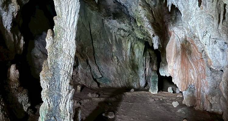 Intérieur faiblement éclairé d'une grotte naturelle aux parois rocheuses rugueuses et aux colonnes.