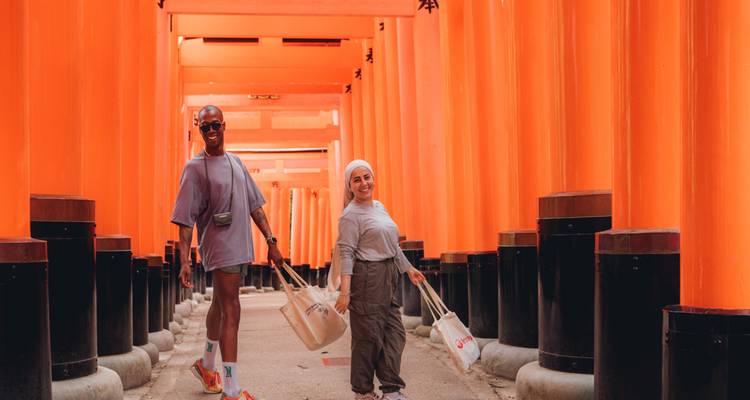 Dos viajeros caminan a través de las interminables puertas torii de color bermellón del Santuario Fushimi Inari.