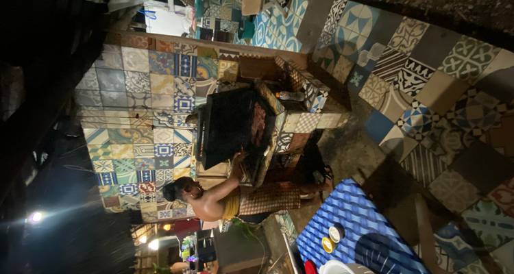 Cuisinier grillant de la viande sur un barbecue à charbon dans une cuisine extérieure carrelée la nuit