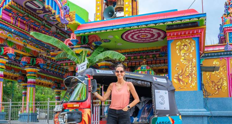 Reiziger poserend met versierde tuk-tuk voor een fel gekleurde hindoetempel gevel.