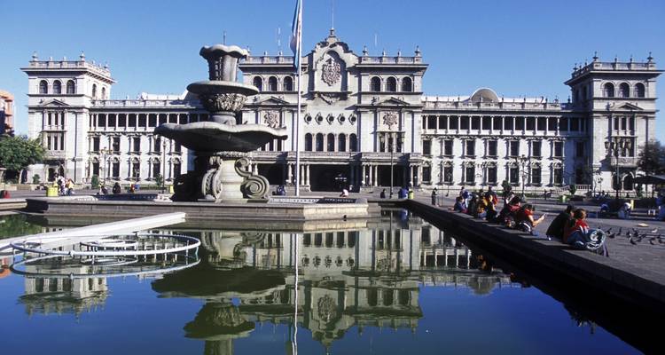 Gran Palacio Nacional de Cultura reflejado en una piscina tranquila en una mañana soleada.