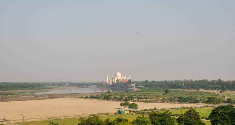 Entfernte Ansicht des Taj Mahal über den Fluss Yamuna bei dunstigem Morgenlicht.