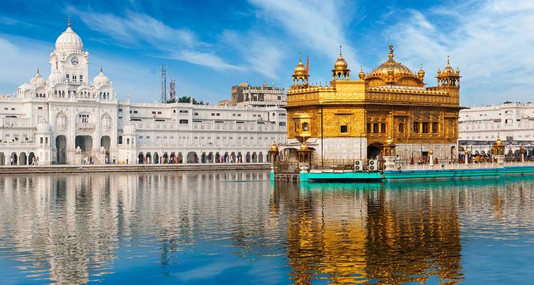 Le Temple d'Or brille aux côtés de son bassin sacré reflétant la lumière sous un ciel bleu éclatant à Amritsar.