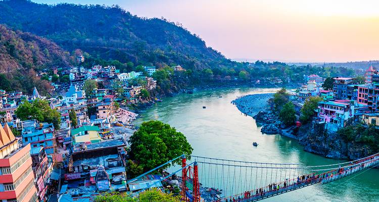 La ville colorée de Rishikesh s'étend de part et d'autre du Gange avec le pont suspendu emblématique au coucher du soleil.