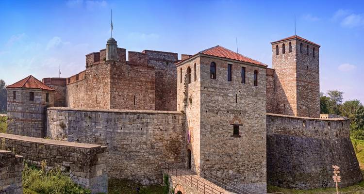 Sturdy stone walls and towers of the medieval Baba Vida fortress rise against a clear blue sky.