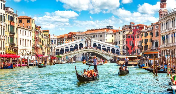 Colorful Grand Canal scene with Rialto Bridge, ornate palaces and gondolas gliding through turquoise water.