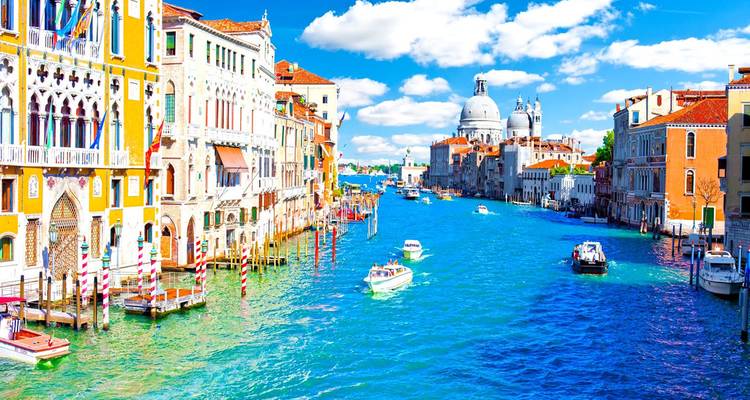 Bright summer view along Venice’s Grand Canal toward Santa Maria della Salute with boats and colorful facades.