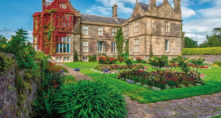 Das historische Muckross House mit rotem Efeu bewachsen und farbenfrohen formalen Gärten.