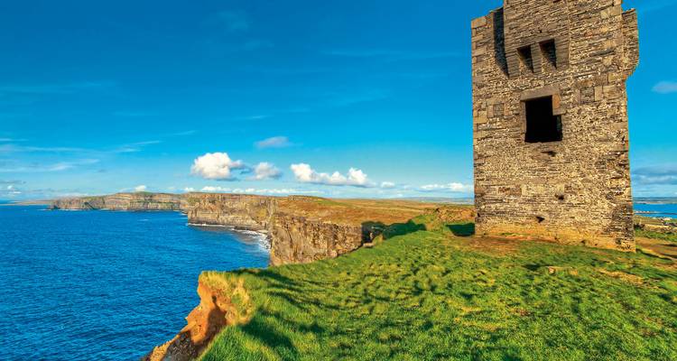 Steinturmruine, die hoch über den Cliffs of Moher thront, mit dem blauen Atlantik darunter.
