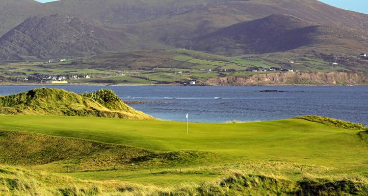 Küstengolfplatz in Kerry mit Bergen im Hintergrund und einer Flickenteppich-Landwirtschaft.