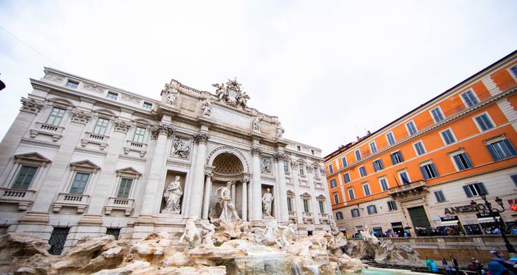 Plano general de la Fontana de Trevi de Roma rodeada de una arquitectura barroca ornamentada y turistas en la plaza.