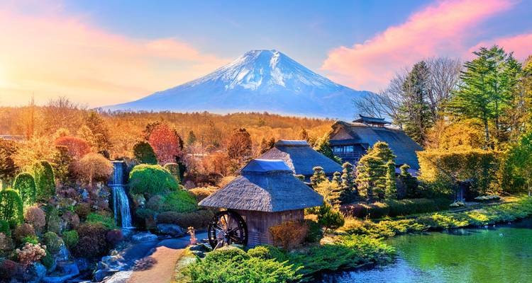Traditional thatched village, pond and waterfall set against Mount Fuji under pastel sunrise skies.