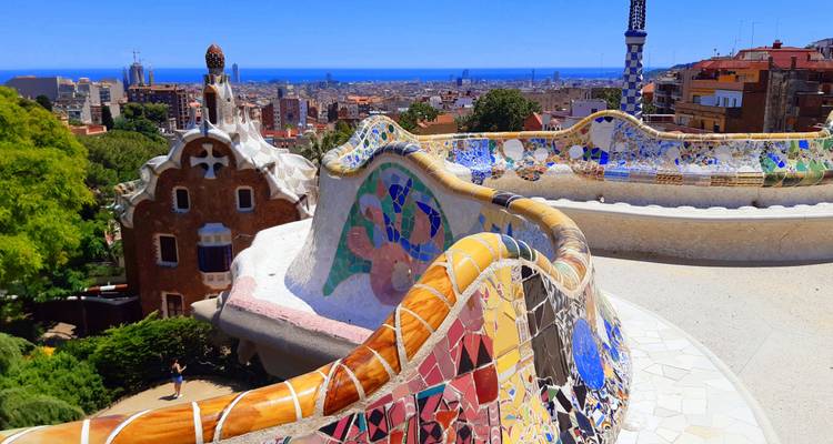 Banco de mosaico icónico y terraza serpenteante del Parque Güell con vistas a Barcelona y el Mediterráneo.