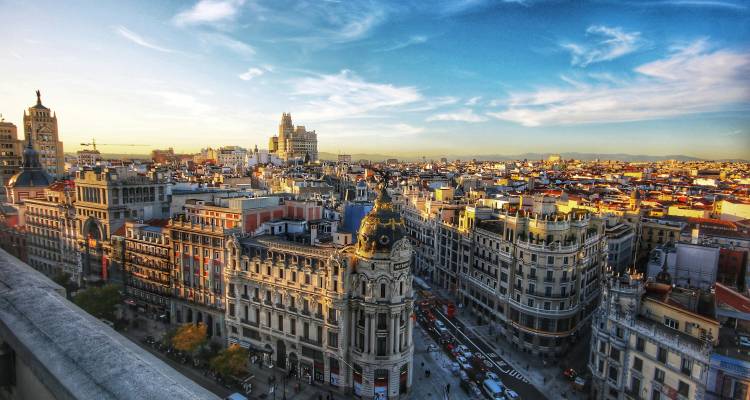 Panoramischer Ausblick vom Dach Madrids Gran Vía mit der Metropolis-Kuppel und endloser Stadtlandschaft unter einem malerischen Himmel.
