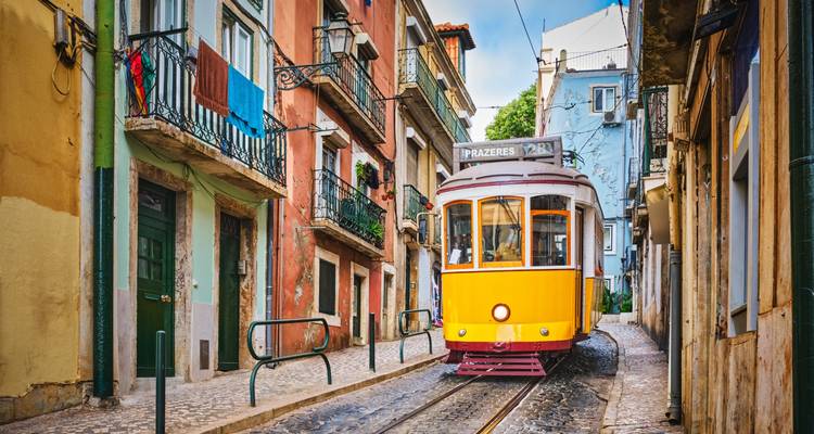 Le célèbre tramway jaune grimpe une ruelle pavée étroite bordée de maisons colorées de Lisbonne.