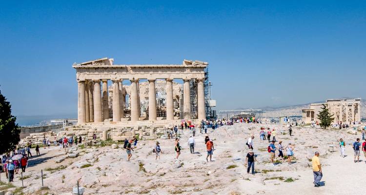 Menschenmengen erkunden das Akropolis-Plateau mit dem Parthenon unter Restaurierungsgerüsten an einem klaren Tag.