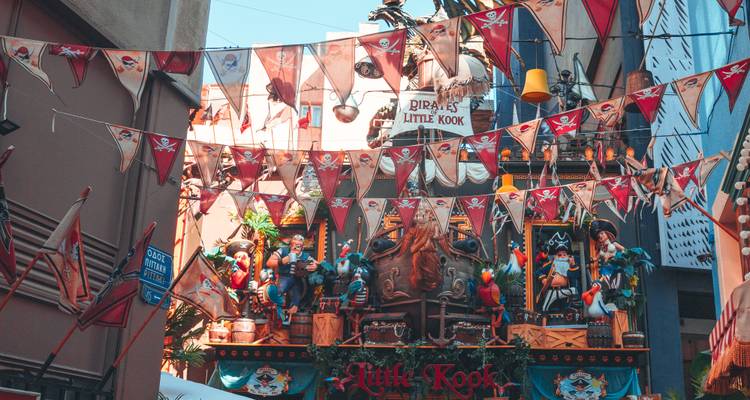 Pirate-themed façade of Little Kook café draped in bunting and colorful figures under blue sky.