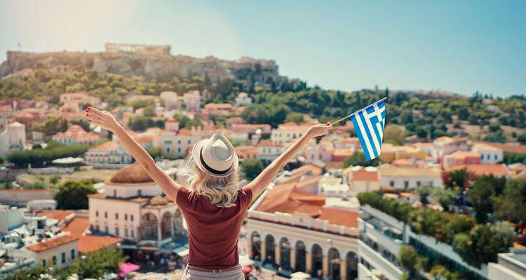 Reiziger met hoed zwaait Griekse vlag uit over het Athese skyline en de Akropolis.