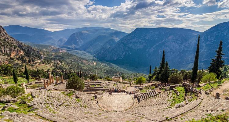 Het oude theater van Delphi kijkt uit over een dramatisch berglandschap onder een gedeeltelijk bewolkte hemel.