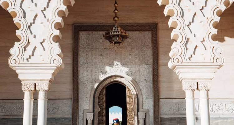 Ornate arched entrance with intricate Islamic geometric designs and hanging lantern in Rabat.