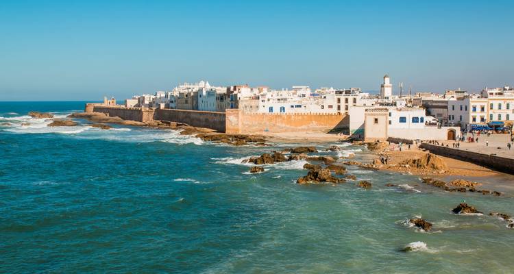 Panoramic view of the white-walled seaside city of Essaouira stretching along the Atlantic Ocean under a clear blue sky