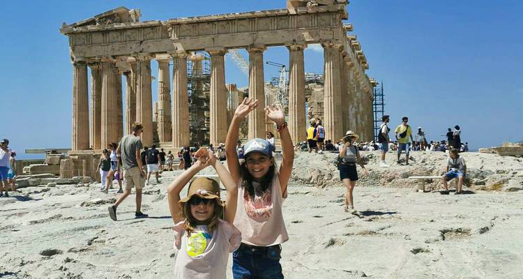 Des enfants posant joyeusement devant les ruines du Parthénon au milieu de la foule des visiteurs.
