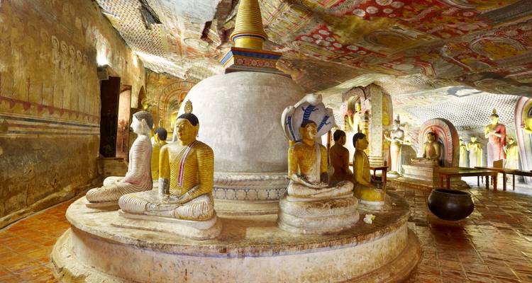 Interior de un antiguo templo en una cueva con estatuas de Buda sentadas rodeando una estupa central.
