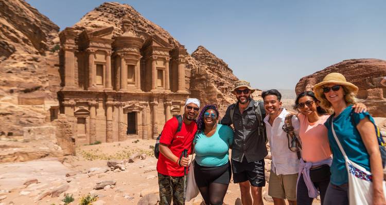 Grupo sonriente de viajeros posando frente al Monasterio de Petra bajo el brillante sol del desierto