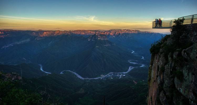 Los visitantes se paran en una plataforma de vidrio espectacular muy arriba del Cañón de Urique al atardecer