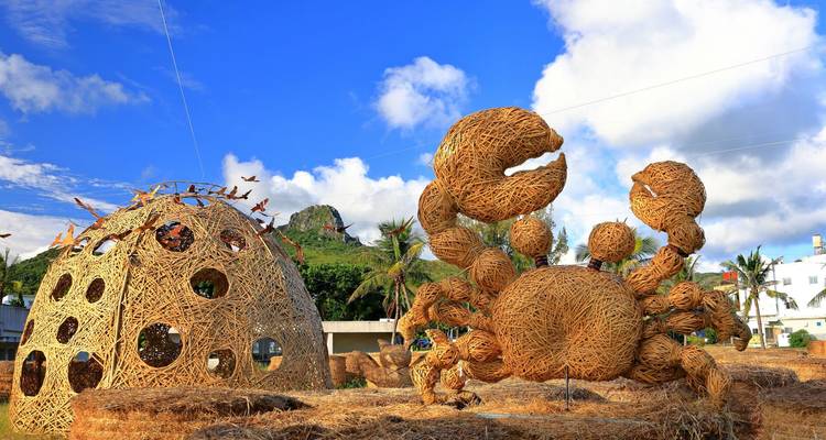 Creative large-scale woven straw sculptures of a crab and dome against a bright blue sky
