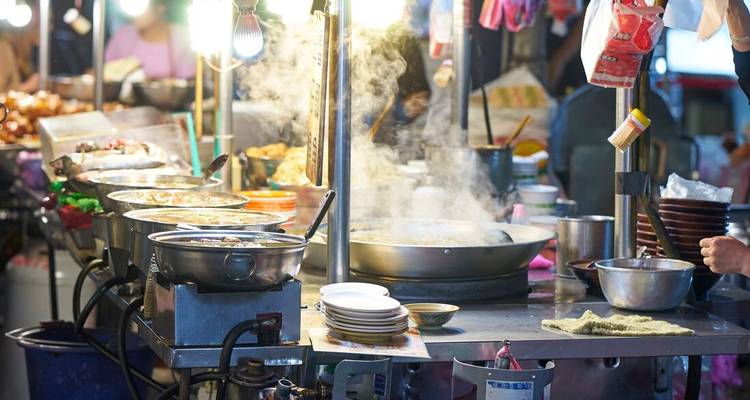 Steam rises from pots and pans at a busy Taiwanese night market food stall