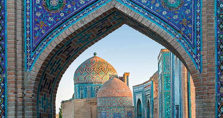 Blaukeramik-Kuppeln und Mausoleen der Shah-i-Zinda-Nekropole, gerahmt durch einen kunstvollen Bogen in Samarkand.