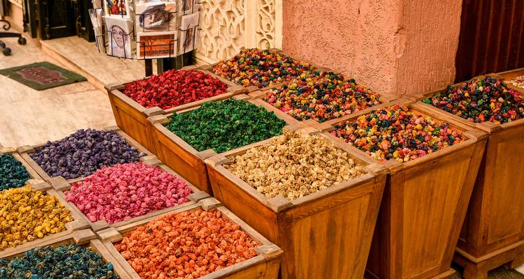 Cajas de madera llenas de flores secas de colores brillantes y especias en un mercado.