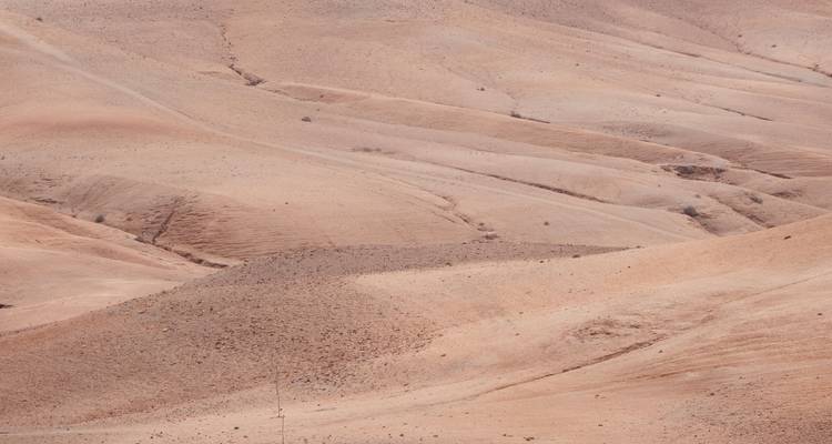 Colinas ondulantes y áridas de color arena en un desierto de piedra bajo la luz del día brillante.