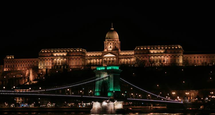 Night view of illuminated Buda Castle above the Chain Bridge reflecting on the Danube