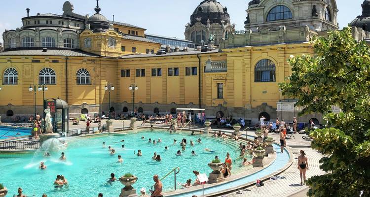 Outdoor turquoise thermal pool surrounded by yellow Neo-Baroque Széchenyi Bath complex and sunbathers