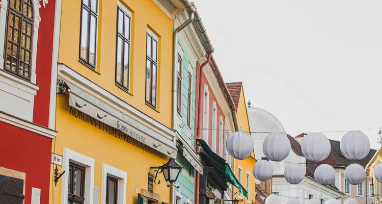 Colorful facades of historic houses adorned with decorative white lanterns in a cobbled street