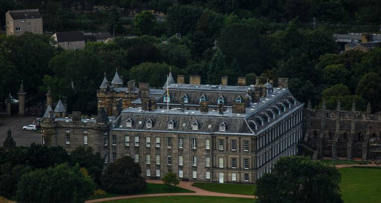 Le majestueux Palais de Holyroodhouse aux toitures crénelées entouré d'arbres luxuriants, vu d'en haut.