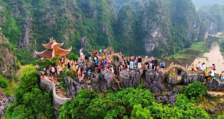 Una multitud grande se reunio en la cima rocosa con una barandilla de dragon serpentino y un pequeño pabellón con vistas al paisaje de karst.