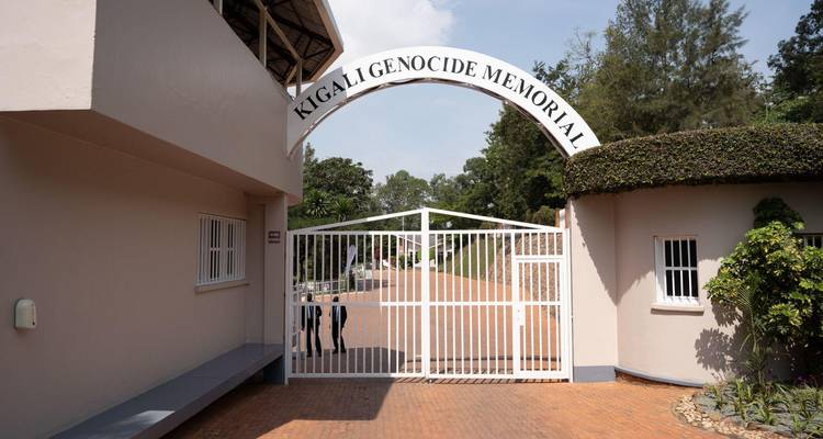Ingangspoort naar het Kigali Genocide Memorial met een witte boog en beveiligingshek.