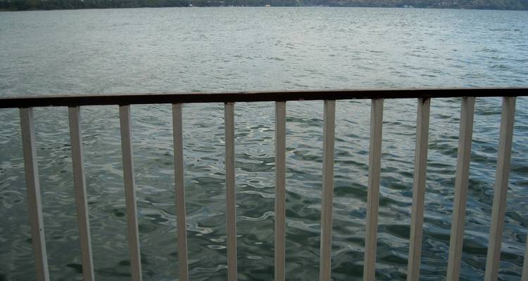 Close view of metal railing overlooking rippling grey lake water on an overcast day.